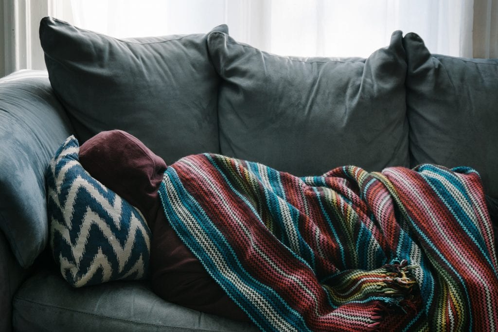 person on couch as COVID-19 symptoms linger