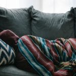 person on couch as COVID-19 symptoms linger